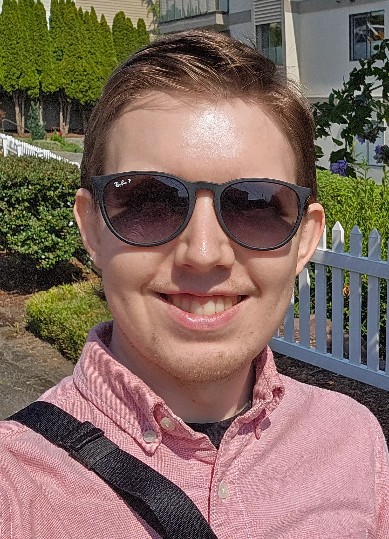 Austin Hagel smiling in sunglasses outside, in front of a white picket fence